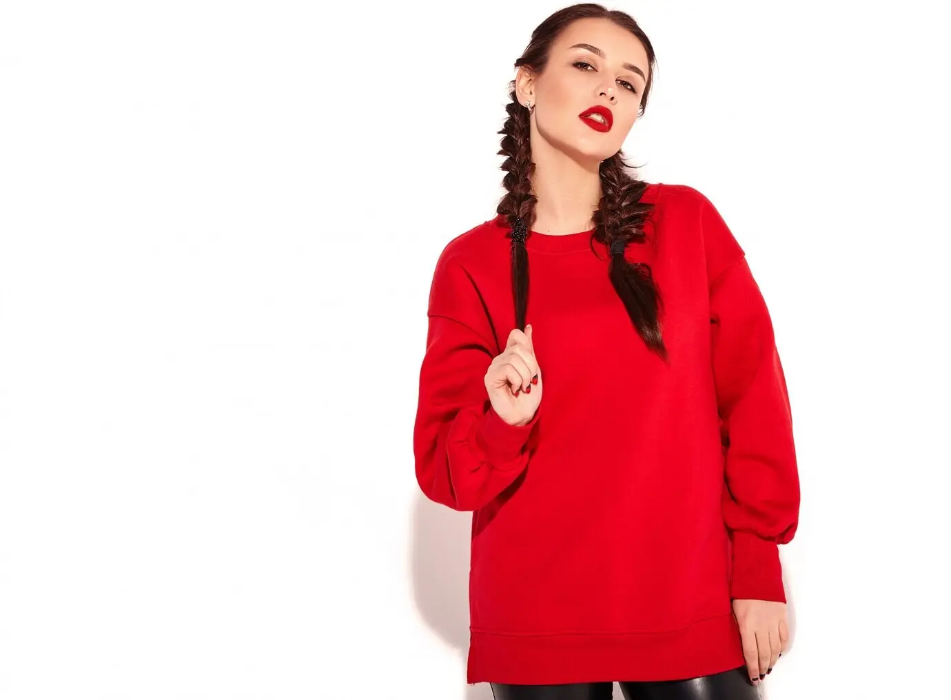 Porträt eines jungen, fröhlich lächelnden weiblichen Models mit auffälligem Make-up und bunten Lippen, zwei Zöpfen und Sonnenbrille, in roter Sommerkleidung, freigestellt.